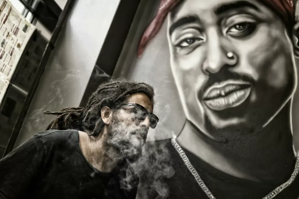 Man close to the portrait of Tupac Shakur. Rap music is in close connection with poetry and often embodies its most contemporary spirit.